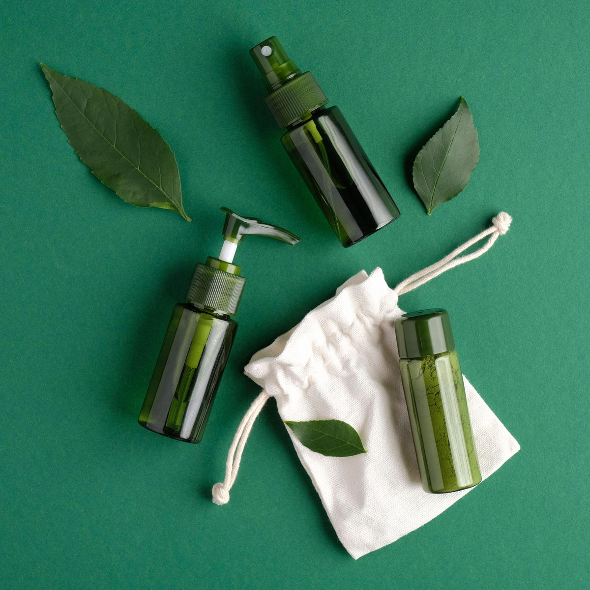 Green personal-care bottles arranged with leaves on a green background